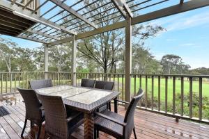 a patio with a table and chairs on a deck at Villa 3br Malbec Villa located within Cypress Lakes Resort in Pokolbin