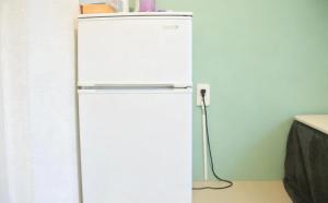 a white refrigerator in a kitchen next to a wall at Hananosato 池袋本店 池袋駅から近く 新宿渋谷銀座へ移動しやすい 周辺に 24 時間コンビニ 昔ながらの銭湯があり 人気の漫画本店も徒歩圏内 多様なタイプの客室を取り揃え 東京観光 都市散策 ショッピングにおすすめ in Tokyo