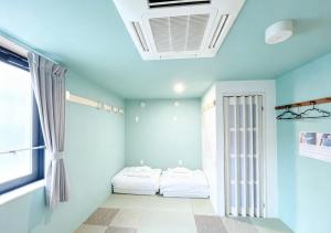 two beds in a room with blue walls and a window at Hananosato 池袋本店 池袋駅から近く 新宿渋谷銀座へ移動しやすい 周辺に 24 時間コンビニ 昔ながらの銭湯があり 人気の漫画本店も徒歩圏内 多様なタイプの客室を取り揃え 東京観光 都市散策 ショッピングにおすすめ in Tokyo