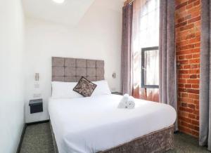 a bedroom with a white bed and a brick wall at Kick back relax stylish space in Nottingham