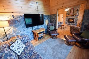 a living room with a couch and a flat screen tv at 6BR/5BA Retreat • Hot Tub • Game Room • Treehouse in Blue Ridge