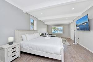 a white bedroom with a large bed and a desk at Balmoral Waterfront Escape at Lake Macquarie in Balmoral