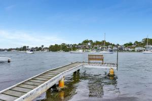 a bench on a dock in the water with boats at Balmoral Waterfront Escape at Lake Macquarie in Balmoral