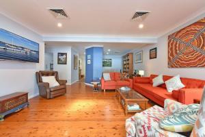 a living room with orange couches and a table at Wangi Dreaming in Wangi Wangi