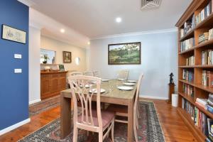 a dining room with a table and chairs and bookshelves at Wangi Dreaming in Wangi Wangi