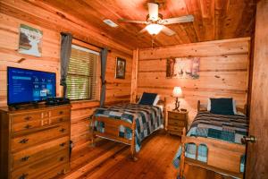 a log cabin bedroom with two beds and a tv at 2BR/1BA Cabin | Hot Tub | Ocoee River Area | Wifi in Copperhill