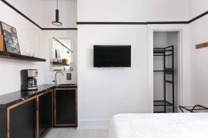 a white kitchen with a tv on a wall at 1BR Escape Queen Bed WiFi & Kitchenette in San Diego