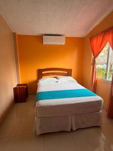 ein Schlafzimmer mit einem Bett und einer orangefarbenen Wand in der Unterkunft Siona Hotel in Atacames