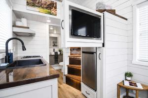 a kitchen with a sink and a tv on the wall at Tiny Home with Private Hot Tub, Zion Adventure Base in Apple Valley +15 photos