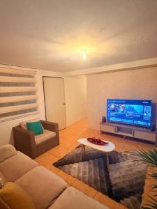 a living room with a couch and a flat screen tv at Quinta María Mercedes in Puembo