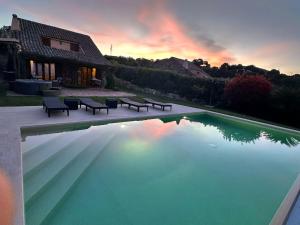 a swimming pool with benches in front of a house at Domus de pedra in Marina di Portisco