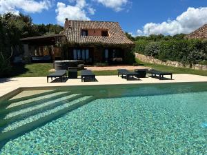 a house with a swimming pool in front of a house at Domus de pedra in Marina di Portisco