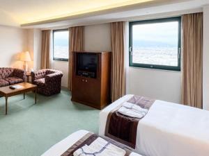 a hotel room with two beds and a television at Hotel LiVEMAX Nagasaki Airport in Omura