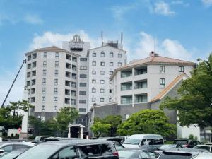 a parking lot with cars parked in front of a building at Hotel LiVEMAX Nagasaki Airport in Omura