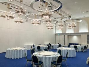 a room with white tables and chairs and chandeliers at Hotel LiVEMAX Nagasaki Airport in Omura +54 photos