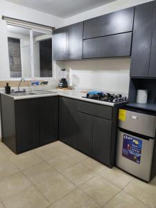 a kitchen with black cabinets and a sink and a stove at Departamento cercano AIFA in Santa Cruz Tecamac