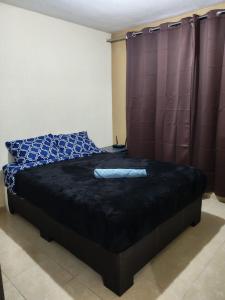 a bedroom with a bed with a black comforter at Departamento cercano AIFA in Santa Cruz Tecamac