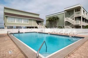 a large swimming pool in front of a house at Sound-Side Condo with Grill Deck & W&D and Shared Pool in Pensacola Beach