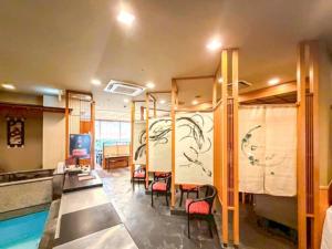 a room with a pool and chairs and a swimming pool at Hotel LiVEMAX Nagasaki Airport in Omura