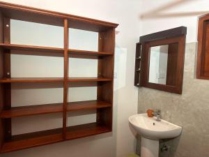 a bathroom with wooden shelves and a sink at Body,Mind & Soul in Bentota