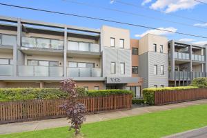 an apartment building with a fence and a yard at Astra Apartments Glen Waverley @ViQi in Glen Waverley