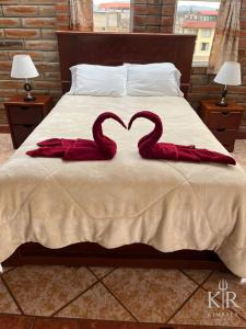 two red swans are forming a heart on a bed at Hostal kimbala in Cotacachi