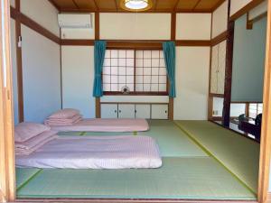 two beds in a room with a large window at 一棟貸切民宿Saisai 3部屋 in Sakai