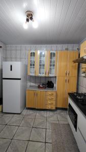 a kitchen with a white refrigerator and wooden cabinets at Propriedade Mendes&Souza - Pinhais in Pinhais