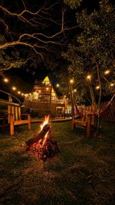 a fire in a park at night with benches and lights at Chalé Suíco Vale do Capão in Palmeiras