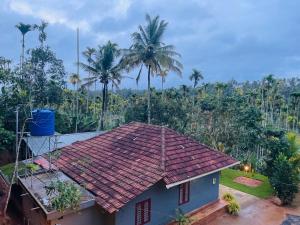 a house with a red roof and palm trees at CHRIS COZY FARM cottage in Wayanad