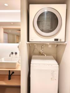 a bathroom with a washing machine and a sink at Hotel Matoma 別館 in Tokyo