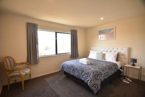 a bedroom with a bed and a chair and a window at Twin Stars in Lake Tekapo