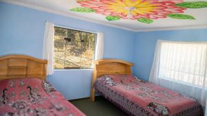 a bedroom with two beds and a flower painted on the ceiling at Dawn House - Lago Titicaca in Ocosuyo