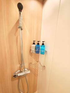 a shower in a bathroom with two bottles of soap at Hotel Matoma 別館 in Tokyo