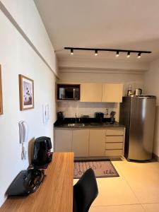 a kitchen with a table and a stainless steel refrigerator at Studio próximo a UFU Sta Monica e Center shopping in Uberlândia
