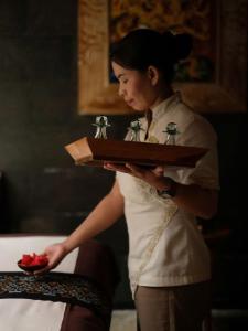 a woman holding a tray with a plate of food at My Eliana Luxury Hotel Saigon Saigon & Spa in Ho Chi Minh City