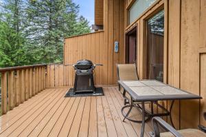 a deck with a grill and a table and chairs at Limber Pine Townhome and 2BDR Stay in Whitefish
