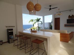 a kitchen with a bar with stools and a view of the ocean at The Siren Resort Nusa Penida - Ocean View Villas in Nusa Penida