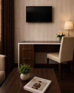 a living room with a desk with a television on the wall at Green City Hotel ШАХРИСАБЗ in Khujand
