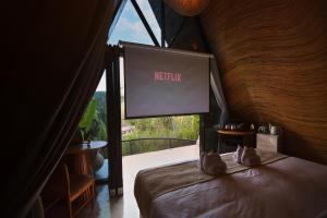 a bedroom with a bed with a large window at Delta Casa Ubud - A-Frame Jungle Retreat with Volcano View and Hot-Tubs in Gianyar
