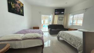 a bedroom with two beds and a chair and a couch at Bungalows Mufrance in San Patricio Melaque