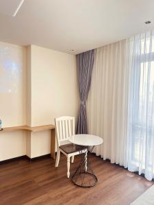 a table and a chair in a room with a window at The Cloud Hotel Bình Dương in Ga Phú Trung