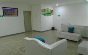 a living room with two white chairs and a couch at Hotel Paraiso Chipichape in Cali