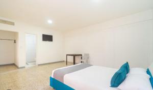 a white bedroom with a bed and a television at Hotel Paraiso Chipichape in Cali