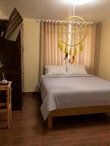 a bedroom with a large bed with a yellow chandelier at La Terraza in Oxapampa