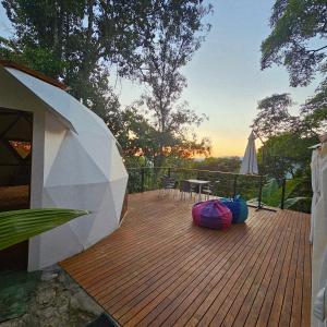 a wooden deck with a table and a umbrella at Elementium Glamping in Cachipay