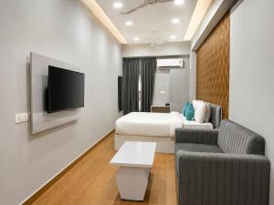 a hotel room with a bed and a couch and a tv at Xenious Smart Suites Greater Noida in Noida