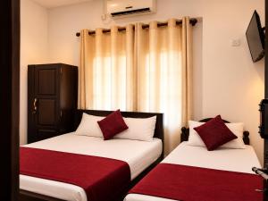 two beds in a room with red and white pillows at Glory Rajarata Lakeside Resort in Anuradhapura