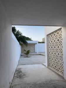 an open doorway to a white building with a palm tree at Minimalist house with pool and patio in Chicxulub