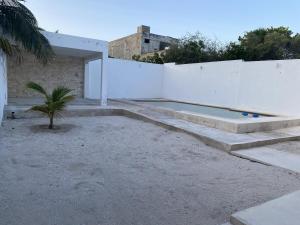 a house with a swimming pool next to a white wall at Minimalist house with pool and patio in Chicxulub